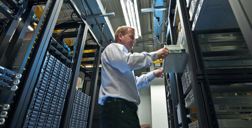 Ein Mann in einem Rechenzentrum, der an einem Server-Rack arbeitet.