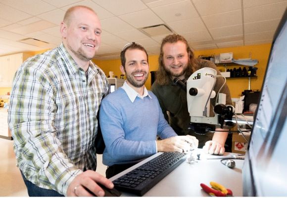 Three researcher in front of a screen in a lab